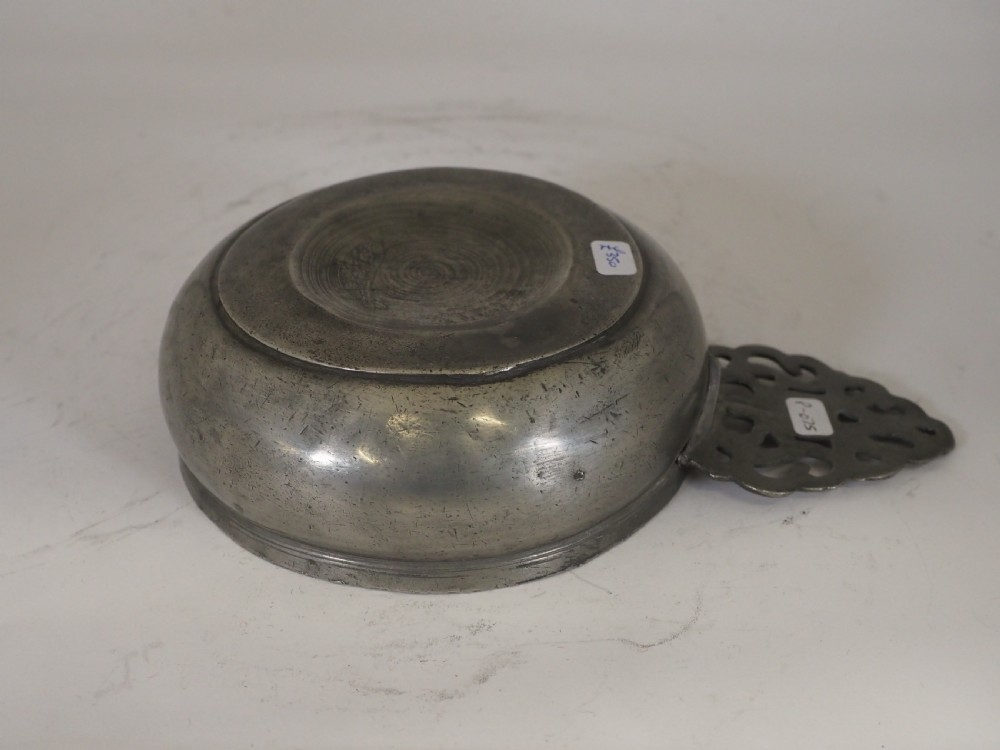 An antique silver-grey pewter porringer bowl featuring a single ornate pierced scrollwork ear handle. View IV