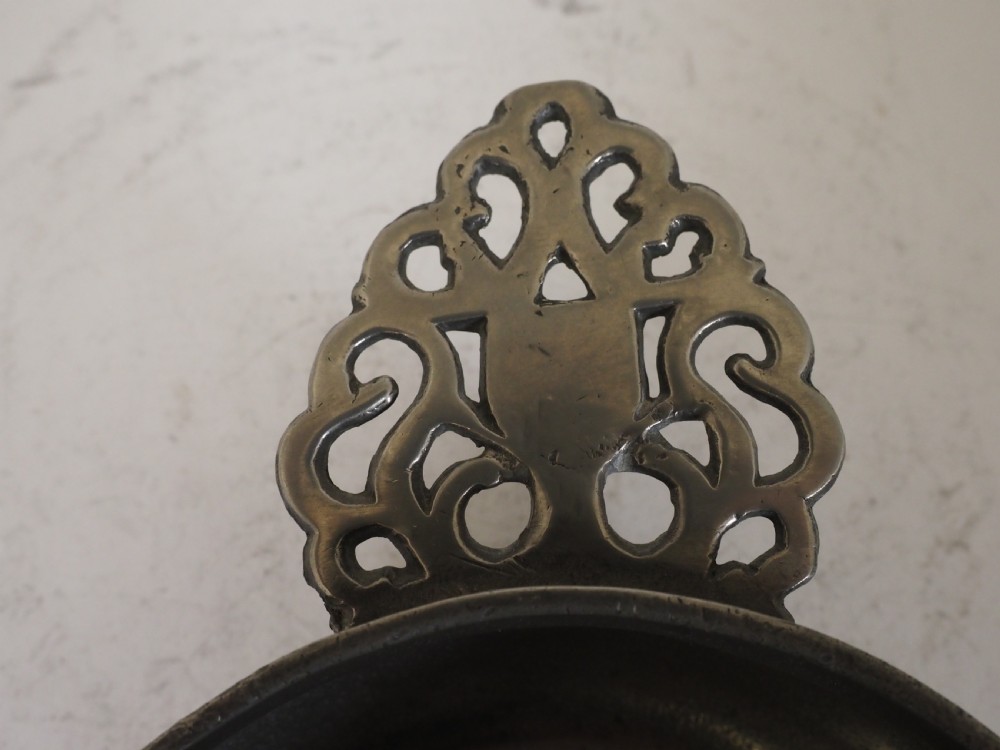An antique silver-grey pewter porringer bowl featuring a single ornate pierced scrollwork ear handle. View IX