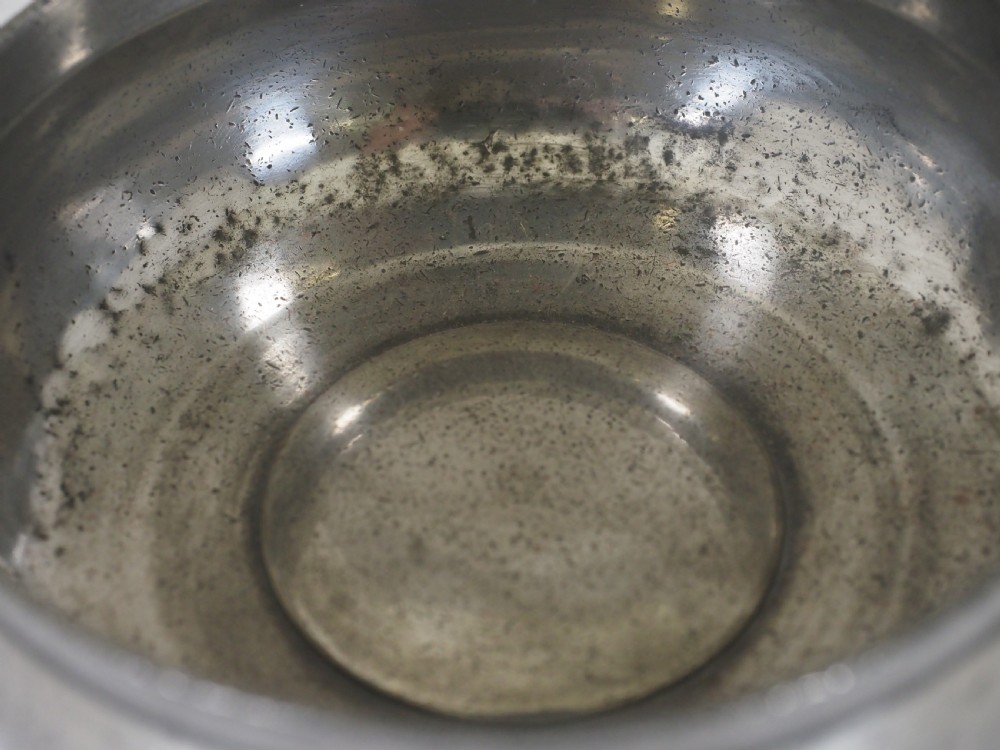 An antique circular pewter porringer bowl featuring a textured interior basin and a decorative pierced scrollwork handle. View VIII