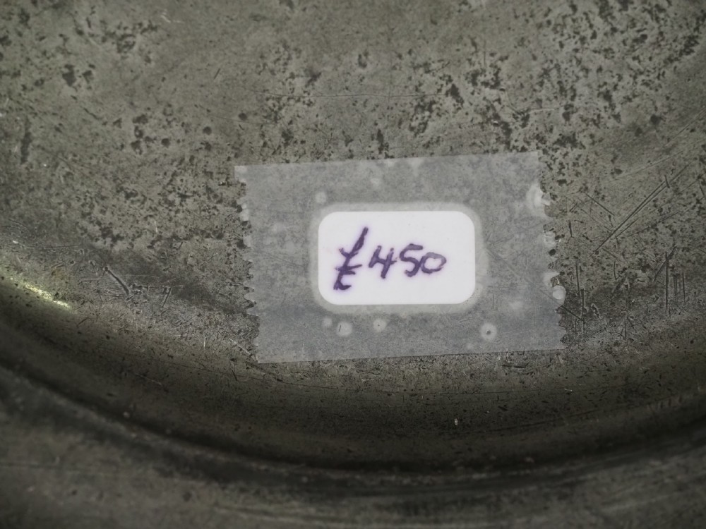 A circular 17th-century English pewter plate displaying a multiple reeded rim with stamped hallmarks near the top edge and initial stamps near the bottom. View VII