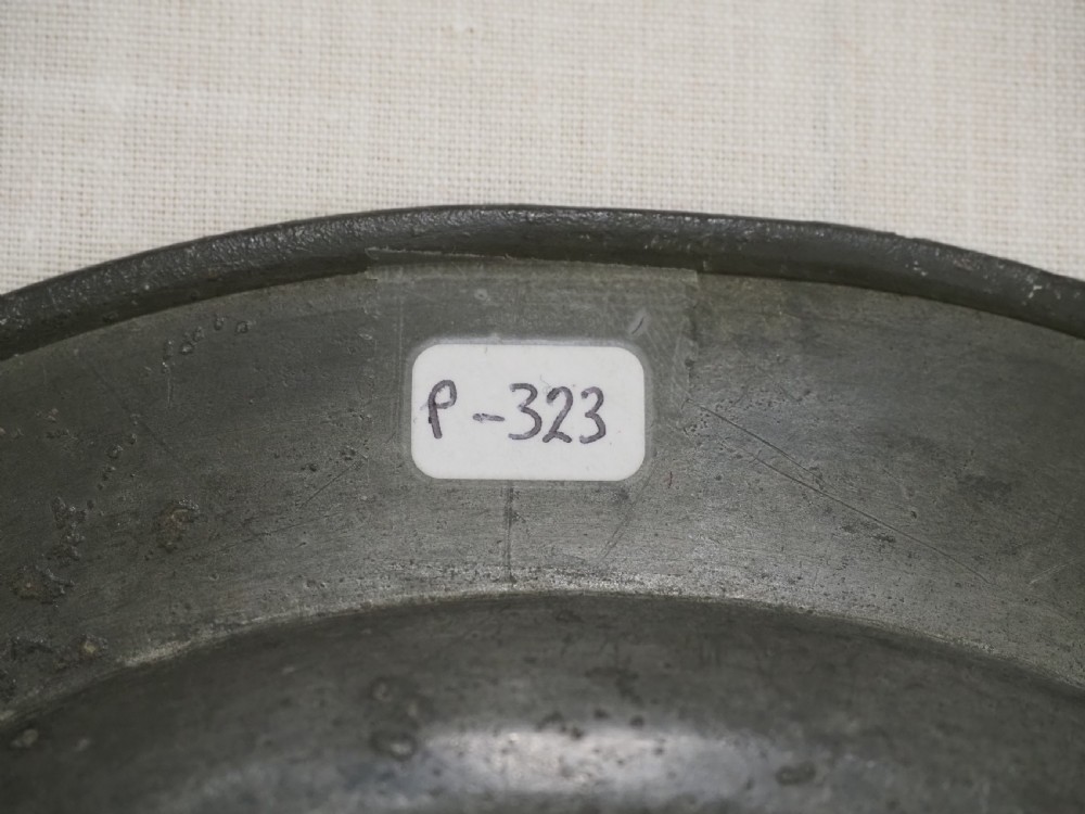 A circular antique pewter plate with a triple reeded rim and stamped touchmarks along the upper border. View VII