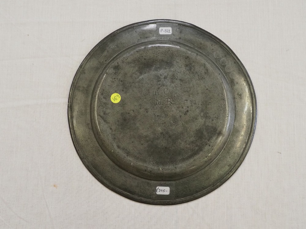 A circular 17th-century English pewter plate featuring an incised rim detail and stamped touchmarks along the upper border. View VI