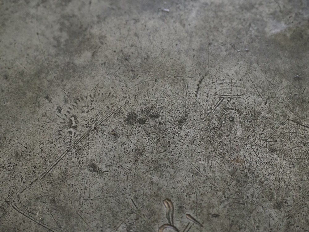 A circular 17th-century English pewter plate featuring an incised rim detail and stamped touchmarks along the upper border. View VII