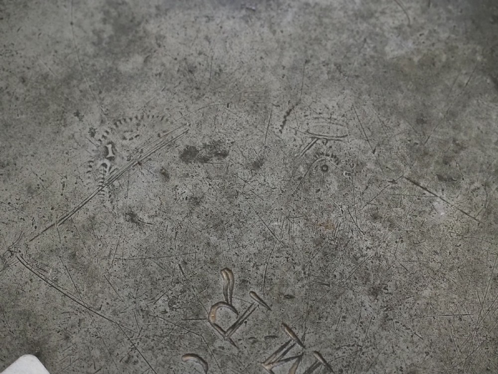 A circular 17th-century English pewter plate featuring an incised rim detail and stamped touchmarks along the upper border. View VIII