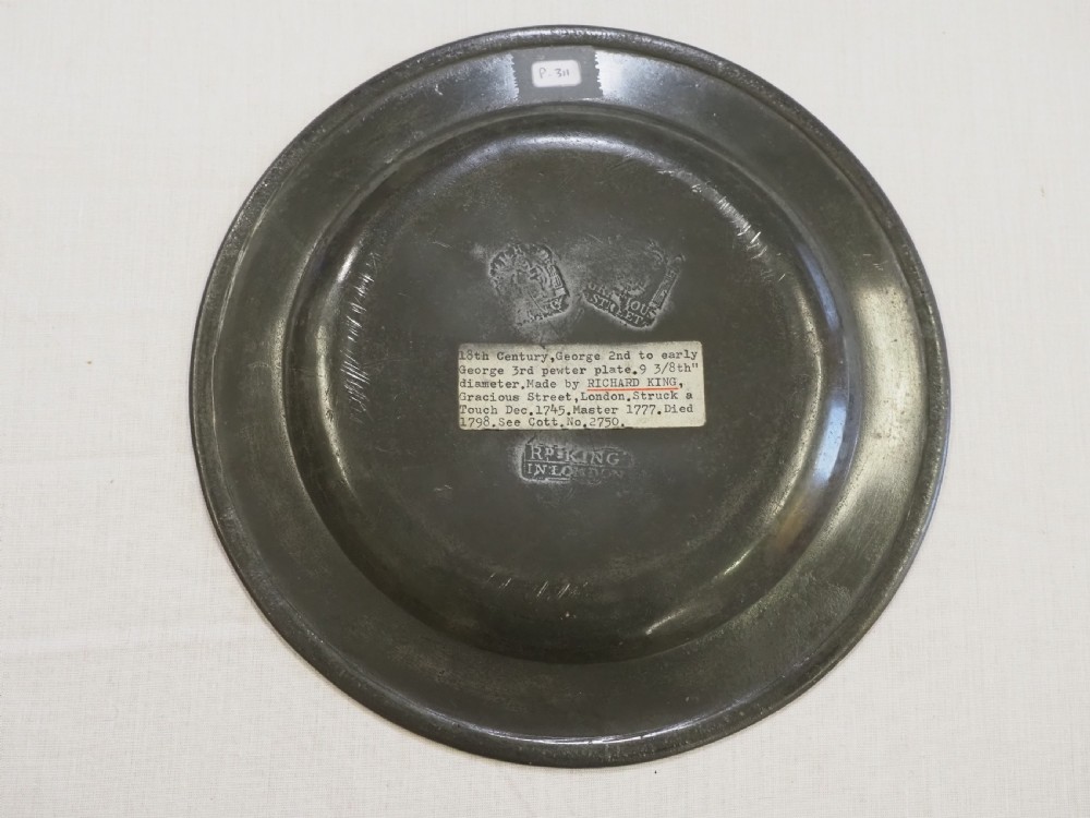 A circular antique pewter plate featuring a wide plain rim, a central shallow well, and subtle surface wear with a silver-grey patina. View IV