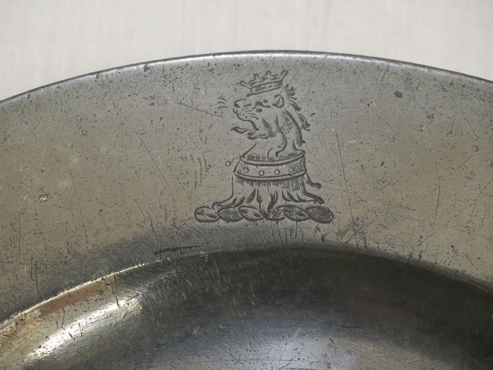 An 18th-century circular English pewter plate with a wide plain rim featuring an engraved lion crest at the top. View II