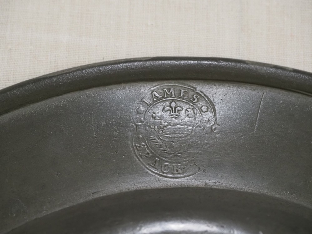 An 18th-century circular English pewter plate with a wide plain rim featuring an engraved lion crest at the top. View V