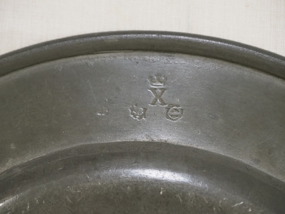 An 18th-century circular English pewter plate with a wide plain rim featuring an engraved lion crest at the top. View VII