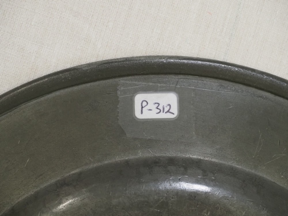 An 18th-century circular English pewter plate with a wide plain rim featuring an engraved lion crest at the top. View VIII