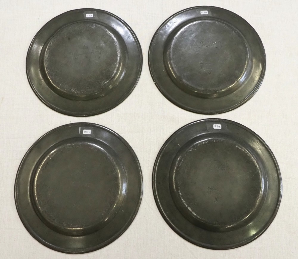 A set of four circular antique pewter plates featuring engraved monograms along the upper rims and a naturally aged grey surface. View VIII