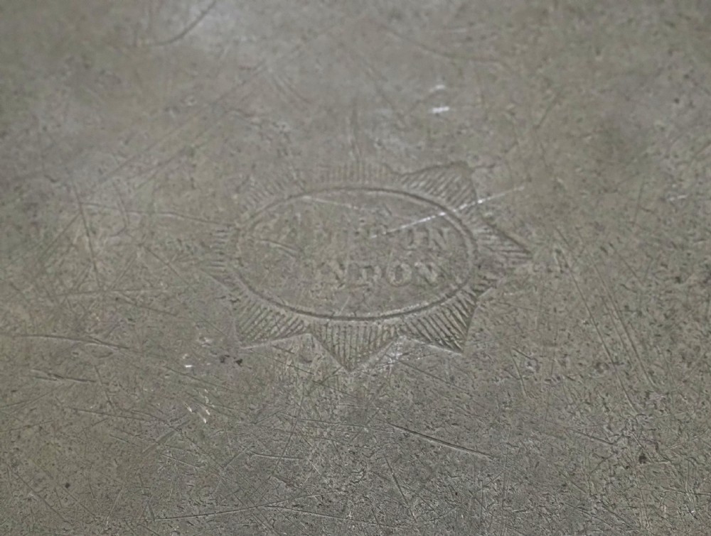 A set of four circular antique pewter plates featuring engraved monograms along the upper rims and a naturally aged grey surface. View X