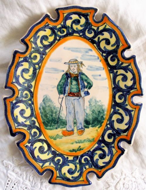 fig 1. A pair of oval tin-glazed earthenware pin trays featuring hand-painted Breton figures surrounded by blue scrollwork and yellow borders with notched edges.