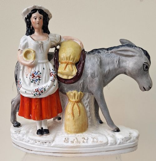 fig 1. A pair of Victorian Staffordshire earthenware pottery figures depicting street traders named Sand and Beesums standing beside saddled grey donkeys.