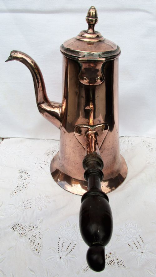 fig 1. An antique Georgian copper coffee pot with a dark turned wooden side handle, curved spout, hinged lid, and brass finial.