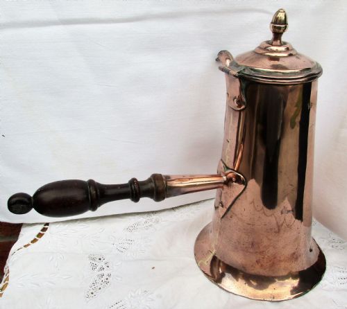 fig 2. An antique Georgian copper coffee pot with a dark turned wooden side handle, curved spout, hinged lid, and brass finial.