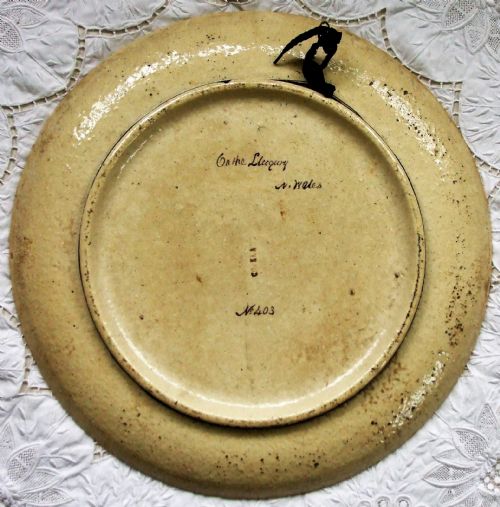 fig 1. A circular Victorian ceramic plaque featuring a hand-painted landscape of a wooden footbridge crossing a river in North Wales.