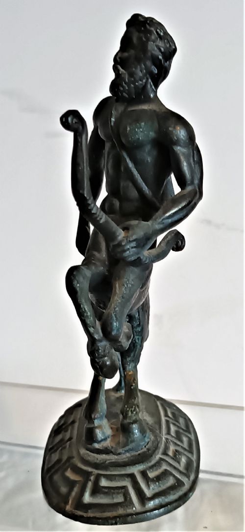 fig 1. A dark patinated bronze figurine depicting a rearing centaur archer holding a bow on an oval base with a Greek key pattern.