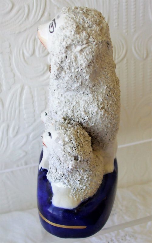 fig 1. An antique Victorian Staffordshire ceramic figure group featuring a mother poodle with two smaller puppies on a cobalt blue base with textured fleece details.