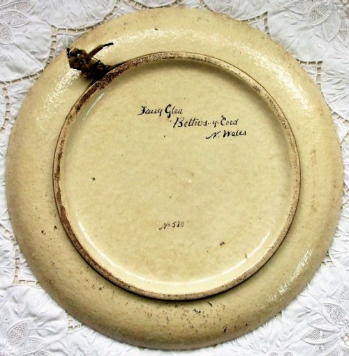 fig 1. A circular Victorian earthenware plaque featuring a hand-painted landscape scene of a river running through a wooded gorge.