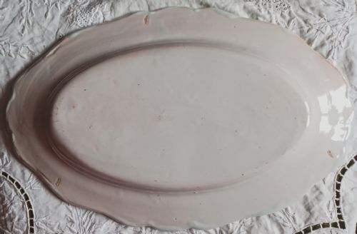 fig 1. An oval cream ceramic faience dish with a scalloped edge, hand-painted with a Breton figure, floral motifs, and the name Pornic.