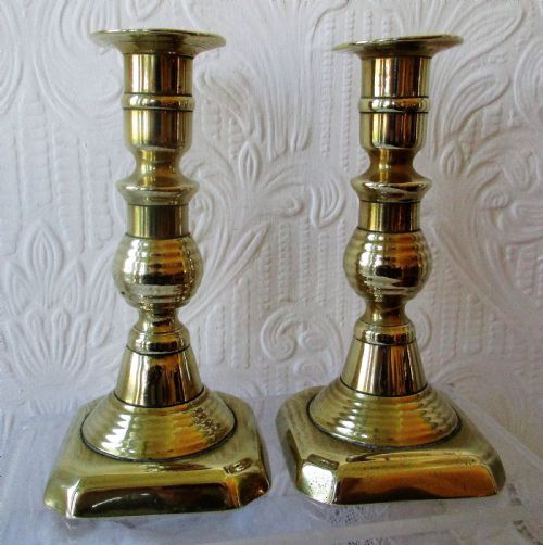 fig 1. A pair of turned Victorian brass candlesticks featuring baluster stems and square bases.