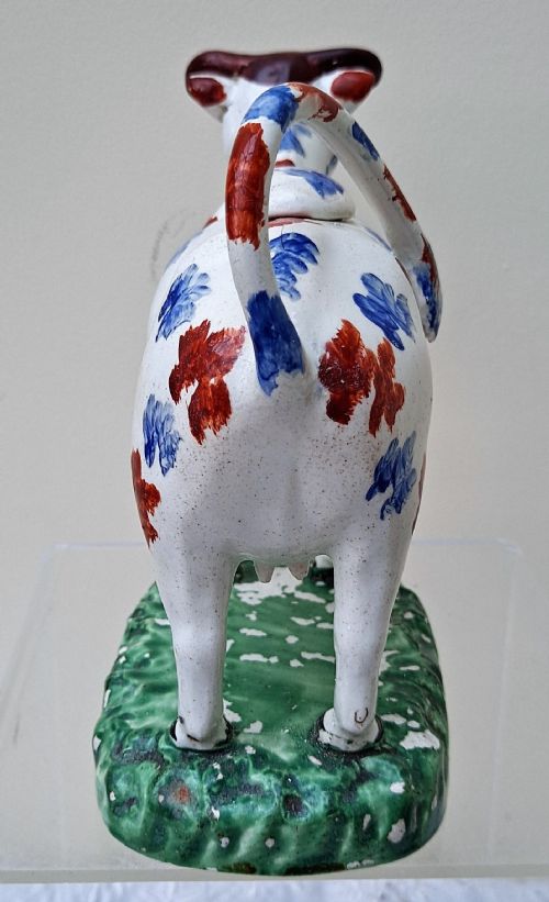fig 1. A Georgian earthenware cow creamer decorated with blue and red hand-painted spots on a green moulded base.