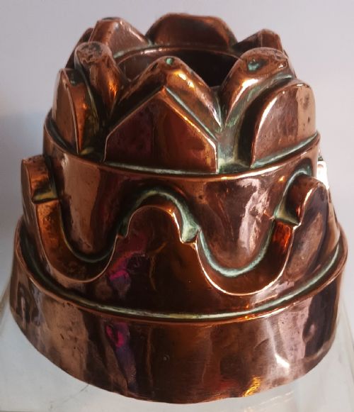fig 1. A tiered Victorian copper jelly mould featuring geometric fluted arches and a central crown pattern.