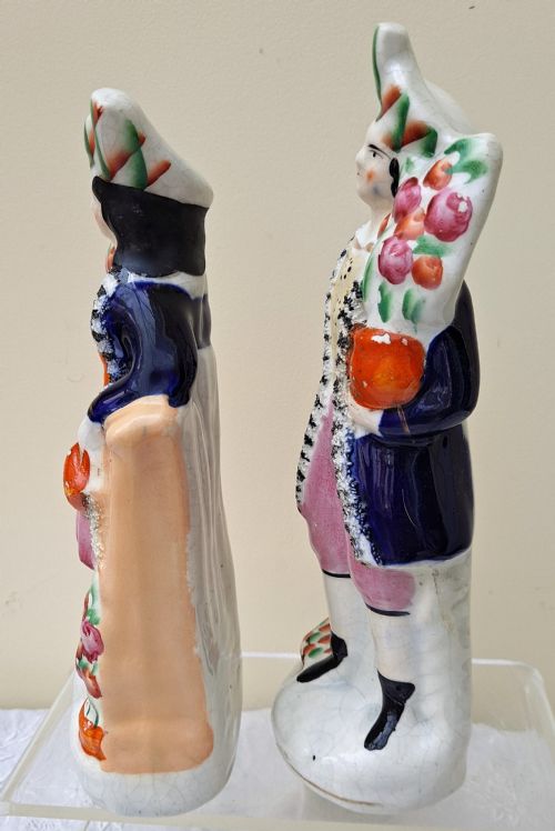 fig 1. A pair of antique Victorian Staffordshire earthenware figures depicting a male and female gardener dressed in colourful attire holding flowers.