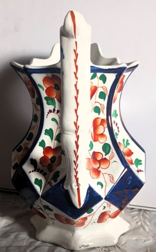 fig 1. A faceted Victorian Gaudy Welsh ceramic jug featuring hand-painted orange floral motifs, cobalt blue panel outlines, and a moulded white handle.