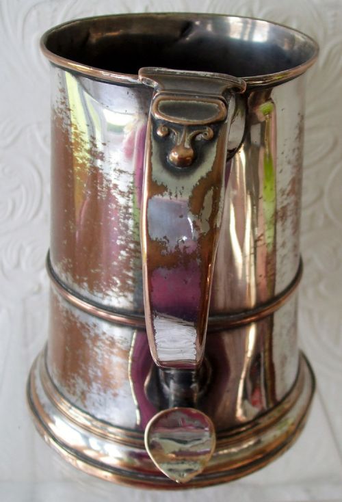 fig 1. An antique Georgian Old Sheffield Plate silver-plated mug showing copper bleed-through, with a tapered cylindrical body, central girdle, and moulded handle.