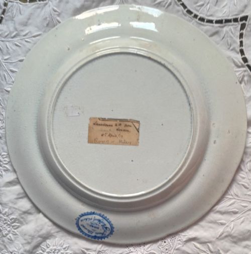 fig 1. An antique circular blue and white transfer-printed earthenware plate featuring a central landscape scene surrounded by a wide floral border.