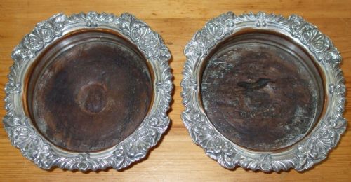 fig 1. A pair of antique Georgian Old Sheffield Plate wine coasters featuring ornate relief borders and turned wood centres with exposed copper tone.