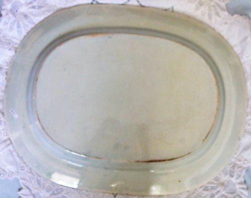 fig 1. An oval antique Georgian earthenware serving platter featuring a blue and white pastoral scene with a piping shepherd surrounded by a floral border.