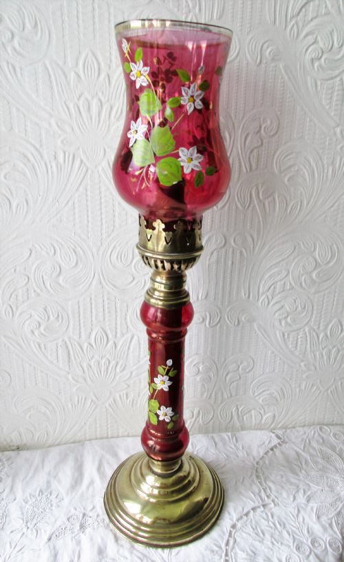 fig 2. A pair of Victorian brass candle lamps featuring hand-painted floral enamel on red cranberry glass shades and stems.