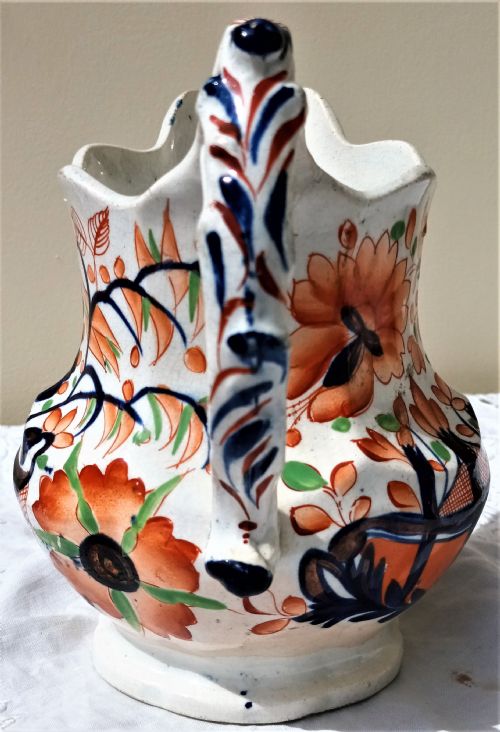 fig 1. An antique Victorian Gaudy Welsh earthenware jug decorated with hand-painted orange floral motifs, cobalt blue details, a scalloped rim, and a molded handle.