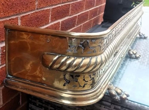 fig 1. A Victorian pierced brass fireplace fender with central rope-twist moulding, pierced fretwork bands, and cast paw feet.