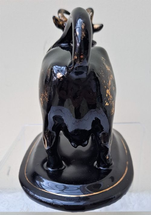 fig 1. A Victorian Jackfield black-glazed ceramic cow creamer featuring gilded detailing and mounted on a contoured oval base.