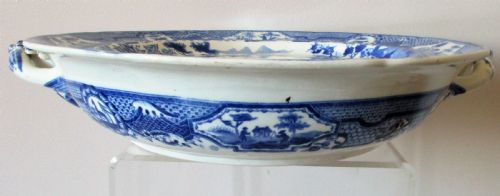 fig 1. An antique Georgian circular blue and white transferware hot-water plate with side handles featuring a central Gothic castle scene and ornate border.