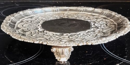 fig 1. A circular Georgian sterling silver salver featuring an intricately chased scroll rim and a central engraved crest.