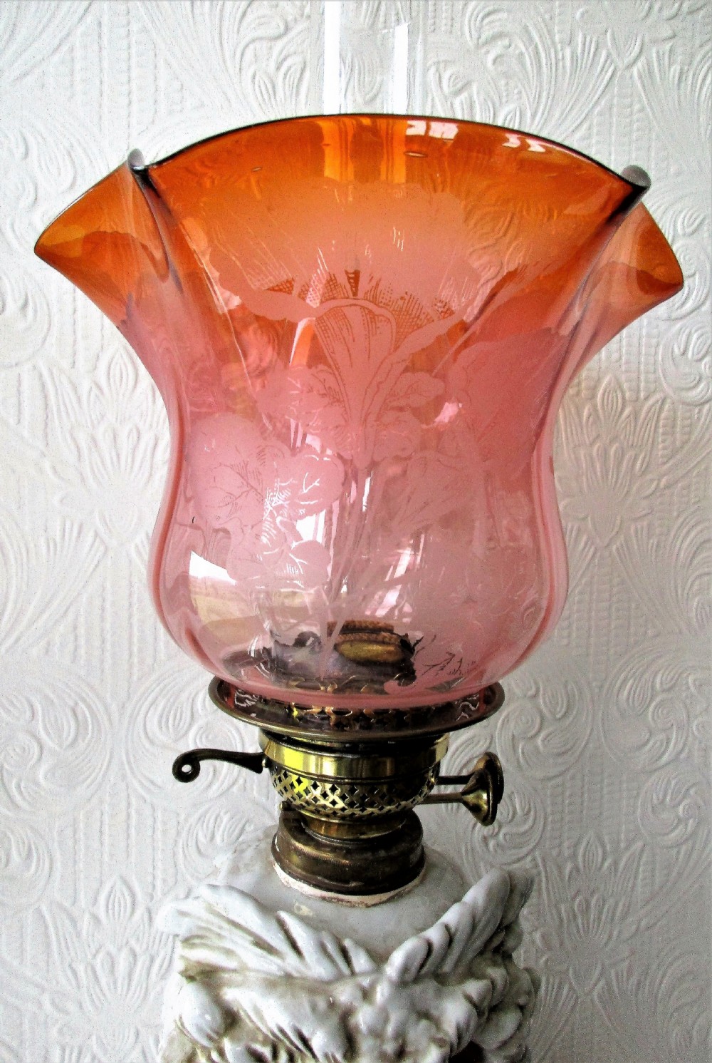 An antique Victorian Sitzendorf oil lamp featuring a sculpted white glazed porcelain owl base with glass eyes, brass burner, clear glass chimney, and a flared, etched pink glass shade. View IV