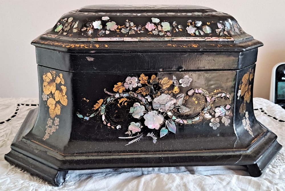 A Victorian black papier-mache tea caddy with mother-of-pearl floral inlay and painted gilt details.