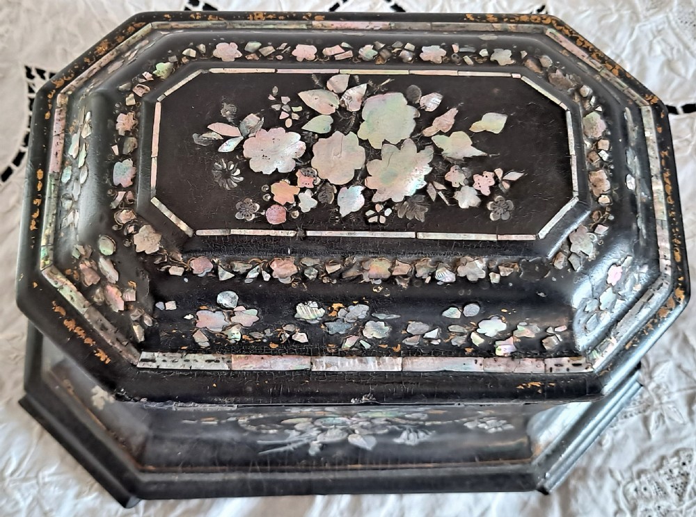 A Victorian black papier-mache tea caddy with mother-of-pearl floral inlay and painted gilt details. View V
