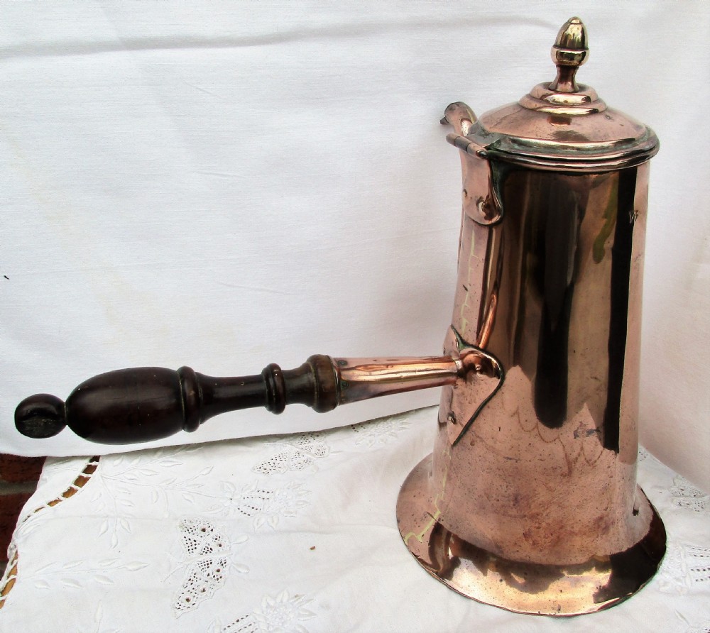 An antique Georgian copper coffee pot with a dark turned wooden side handle, curved spout, hinged lid, and brass finial. View III