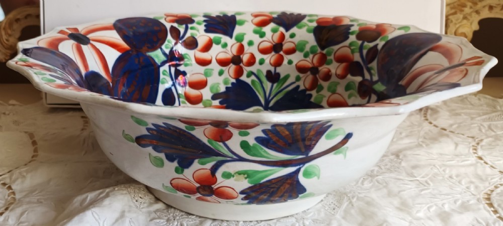 An octagonal Victorian ceramic wash basin painted with red and green floral motifs, cobalt blue leaves, and metallic copper lustre accents on a white earthenware base. View II