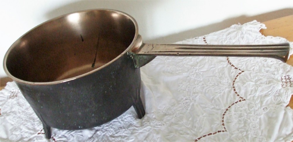 An antique Georgian cast bronze posnet skillet featuring three short legs, a long grooved handle, and a polished interior. View V