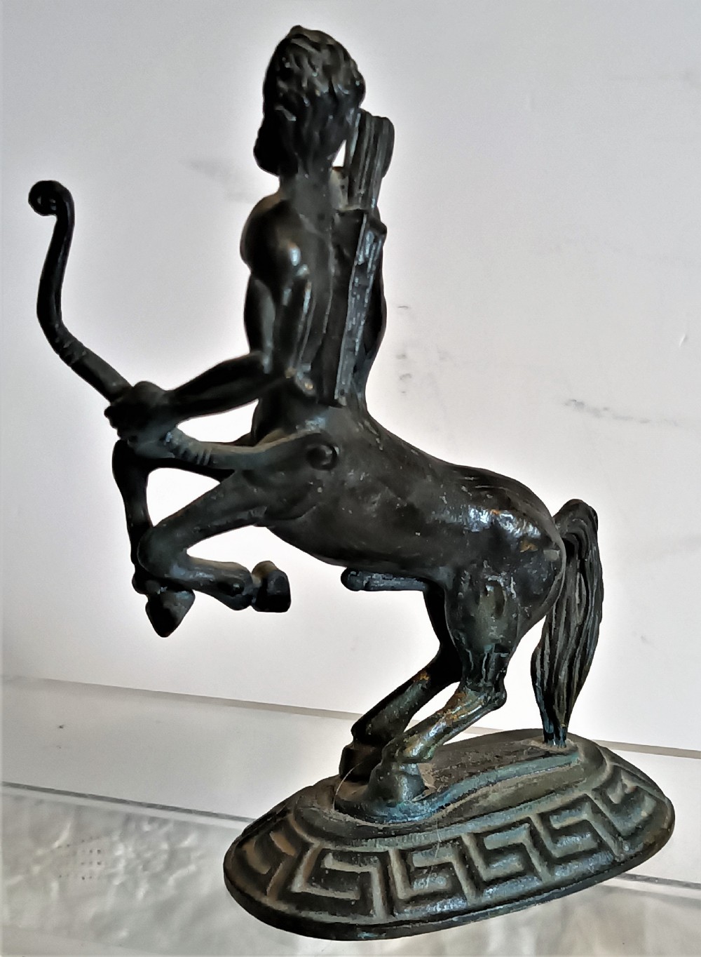 A dark patinated bronze figurine depicting a rearing centaur archer holding a bow on an oval base with a Greek key pattern. View III