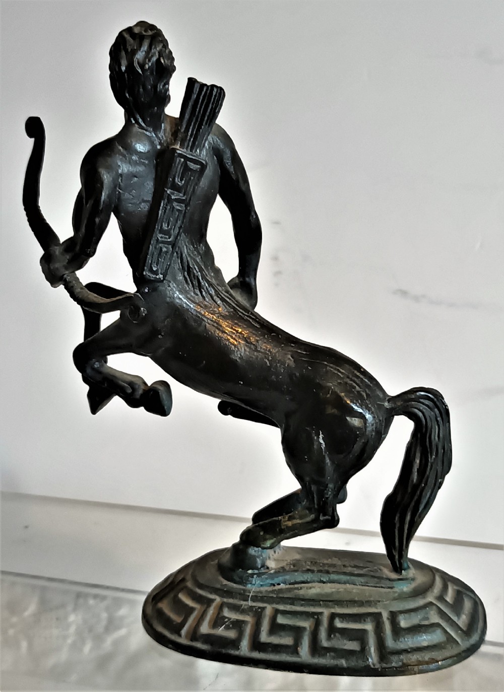 A dark patinated bronze figurine depicting a rearing centaur archer holding a bow on an oval base with a Greek key pattern. View IV