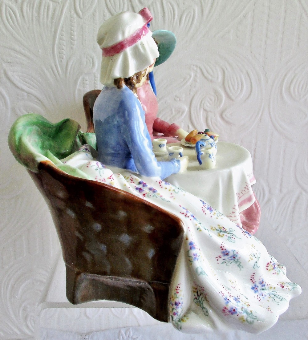 A glazed Royal Doulton porcelain figurine depicting two women in 19th-century attire seated at a tea table. View IV