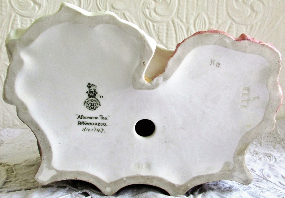 A glazed Royal Doulton porcelain figurine depicting two women in 19th-century attire seated at a tea table. View V