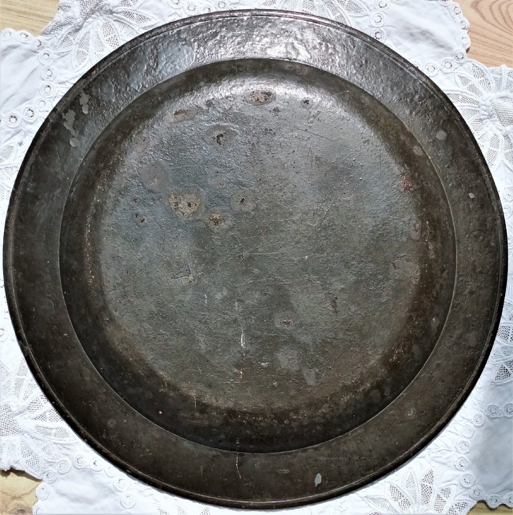 A circular 18th-century English Georgian pewter charger plate featuring a wide flat rim and a weathered dark grey oxidised patina. View II